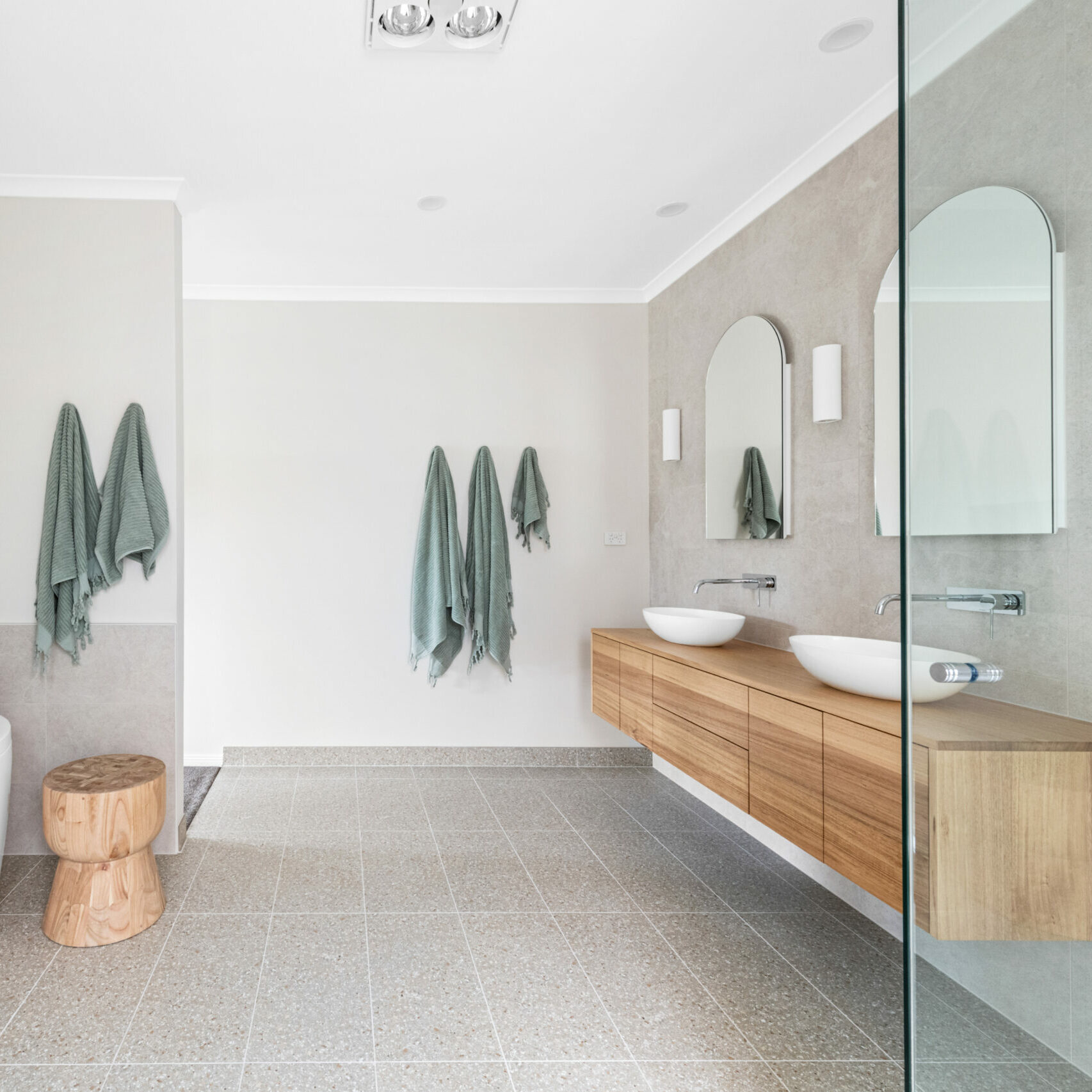 12 Clendon Street Berwick large bathroom, with wooden vanity, cabinetry, bowl basins, arched mirrors, spa bath with sage green towels